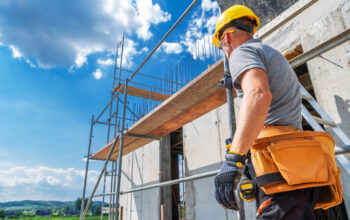 Trabalhador da construção civil utilizando a locação de andaimes em obra para aumentar a produtividade e segurança