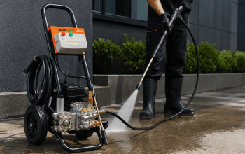 Profissional utilizando lavadora de alta pressão para limpeza de área externa, demonstrando a versatilidade do equipamento em serviços além da limpeza de obras.